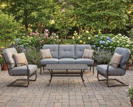Madison sofa, 2 c-spring chairs, and coffee table on a patio with flowers and trees behind.