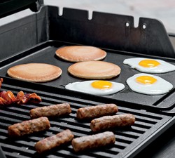 Griddle on grill with sausage, pancakes, and eggs.