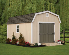 12x16 Painted Deluxe Dutch Barn in Beige Siding, White Trim, Brownstone Shingles, Pequea Green Door, in a backyard.