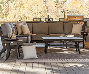 Mayhew Coffee and End Table with Right arm sofa, left arm loveseat, and corner sectional all in black on trex deck with fall trees behind.